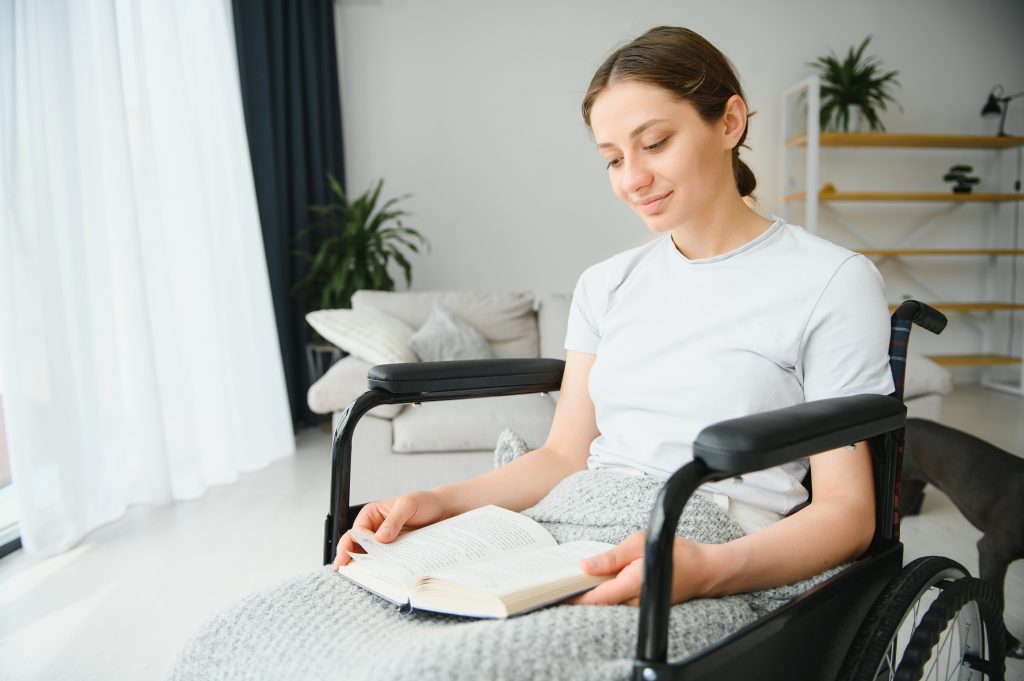 Woman in wheelchair reading book at home.
