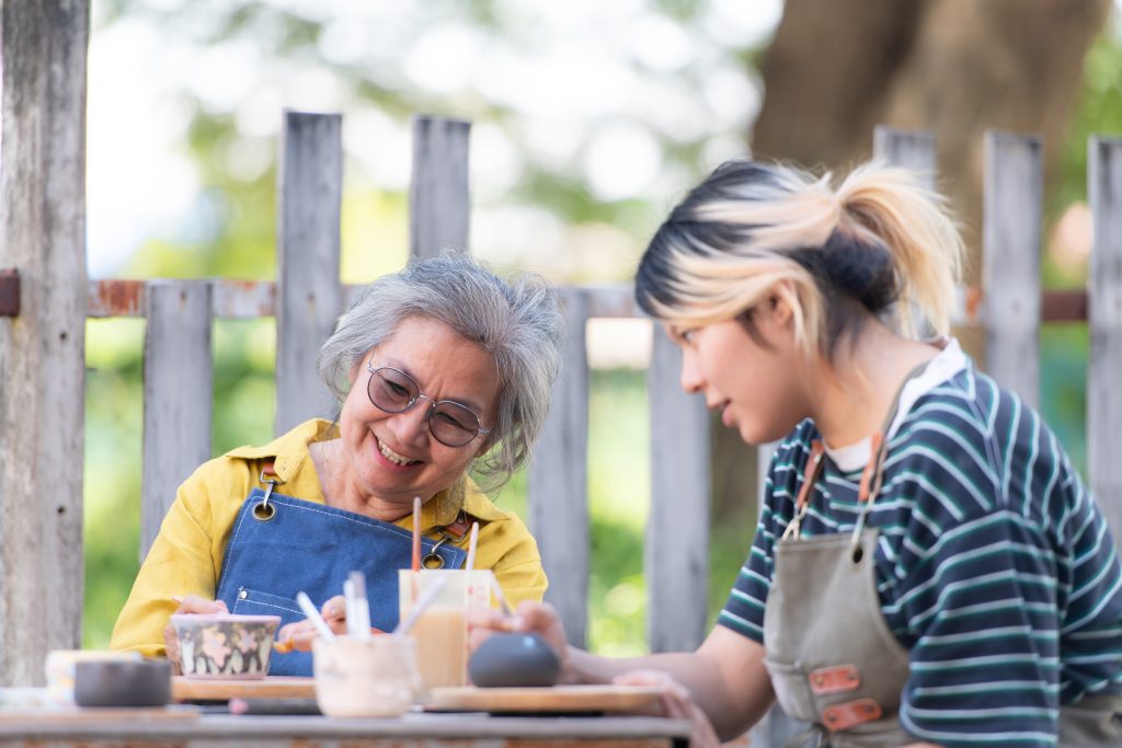 Woman engaged in pottery workshop with female support worker