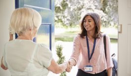 Senior woman greeting female support worker at home